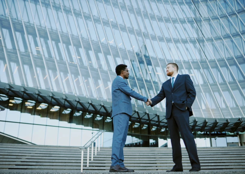 Two men in suits greeting each other.